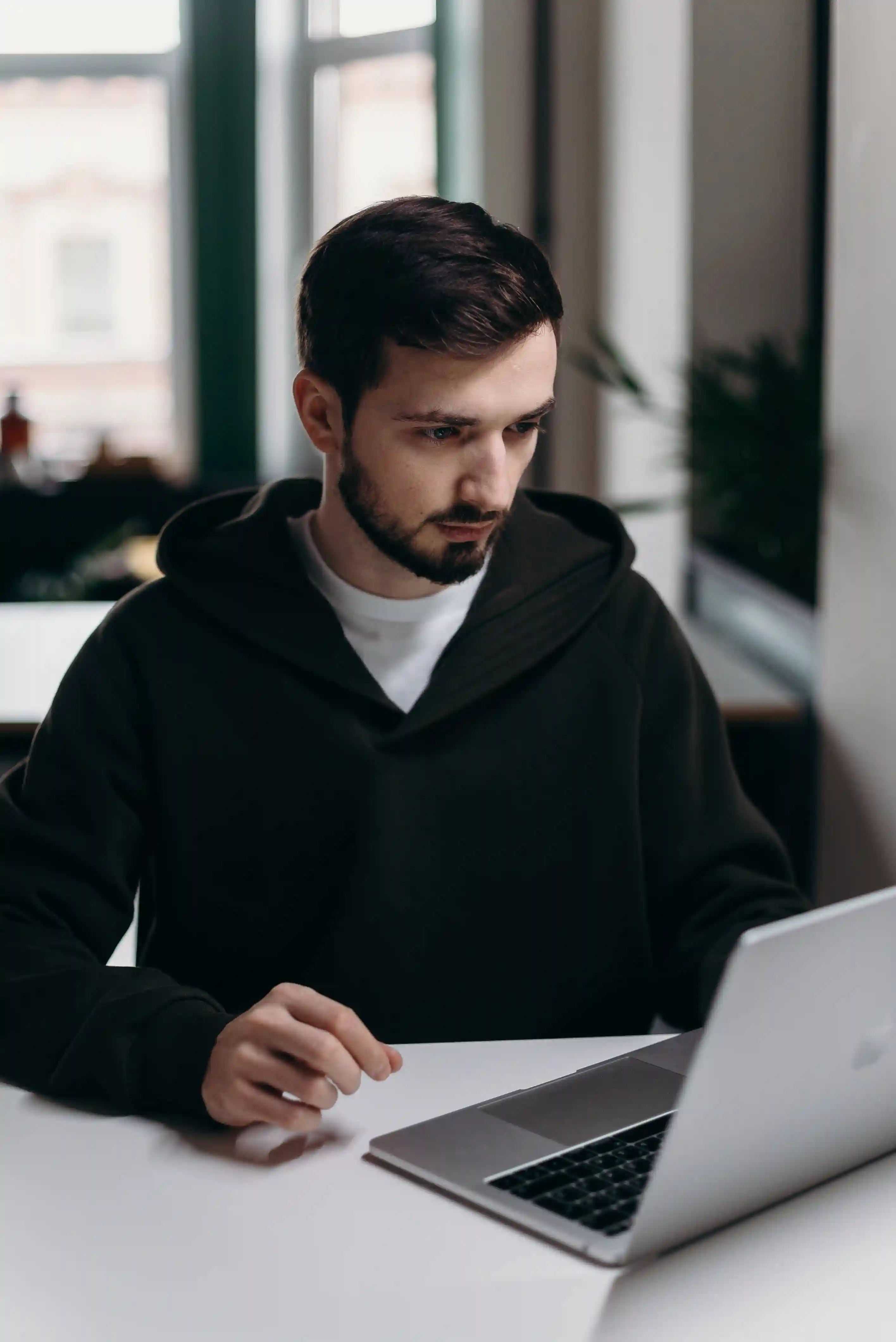 Man in black hoodie using macbook